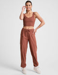 Woman wearing Brown Peak Pant™ with side patch cargo pockets, paired with a matching crop top and cream sneakers.