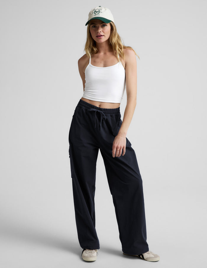 Woman wearing Java Peak Pant™ with side zipper cargo pockets, paired with a white tank top and baseball cap.