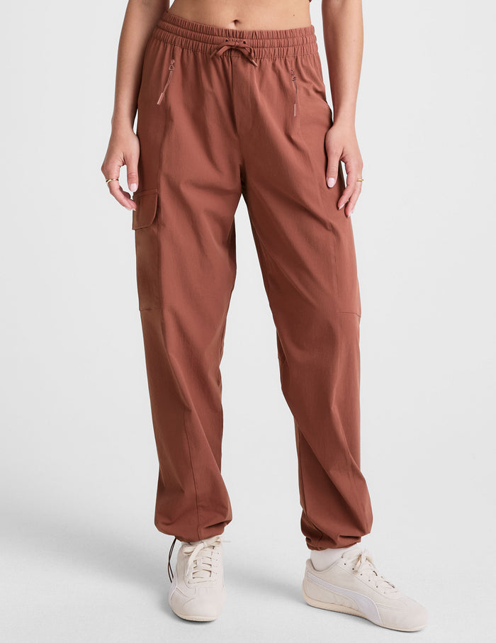 Woman wearing Brown Peak Pant™ featuring an elastic drawcord waist and cargo pockets, paired with cream sneakers.