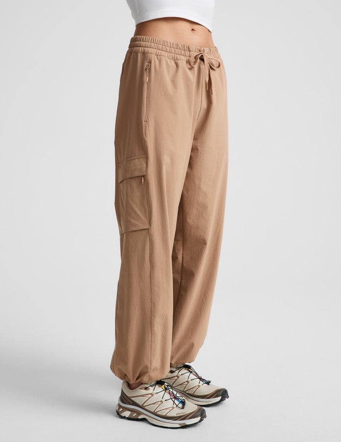 Woman wearing Java Peak Pant™ from a side profile, paired with a white crop top and tan hiking sneakers.