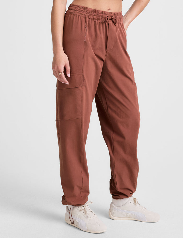 Woman wearing Brown Peak Pant™ with tan sneakers and a matching crop top, featuring cargo pockets and an elastic waist.