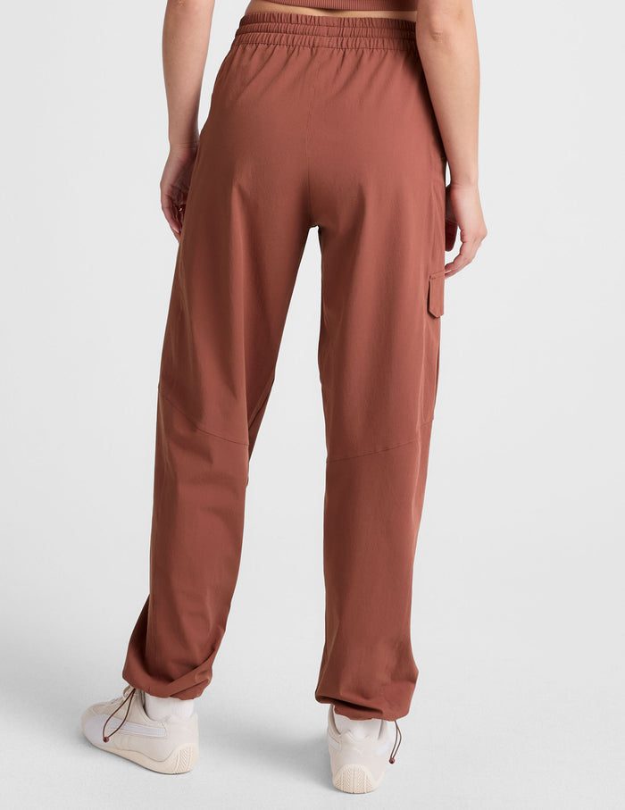Rear view of woman wearing Brown Peak Pant™ with elastic waistband and bungee hem, paired with white sneakers.