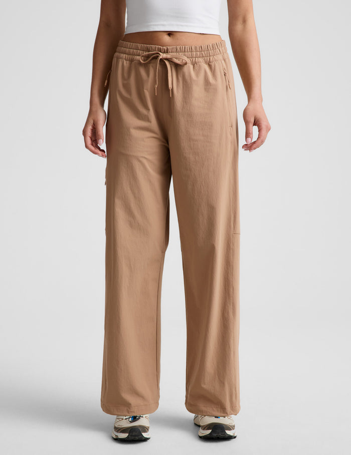 Woman wearing Java Peak Pant™ with a white crop top, featuring an elastic waistband with drawcord and side zipper pockets.
