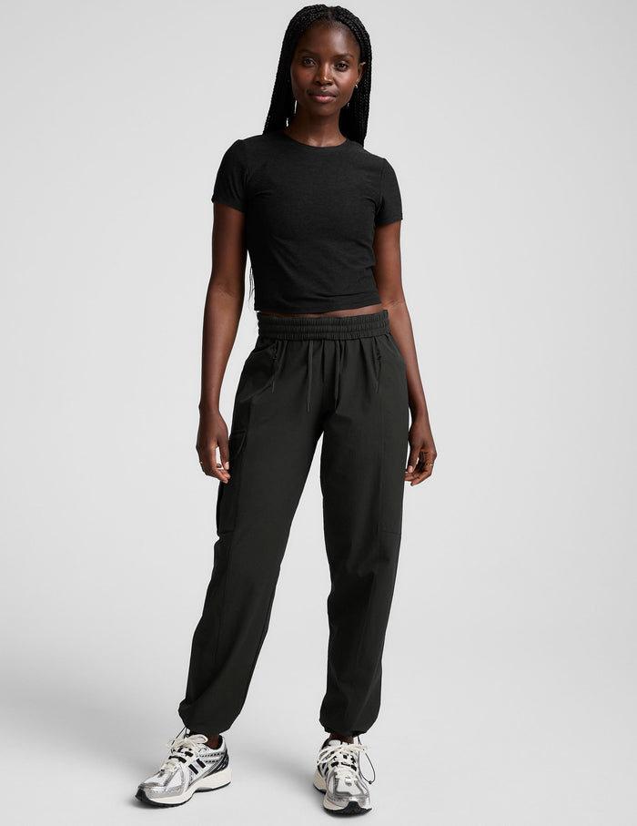 Woman wearing Brown Peak Pant™ with cargo pockets and elastic waistband, paired with a black t-shirt and sneakers.