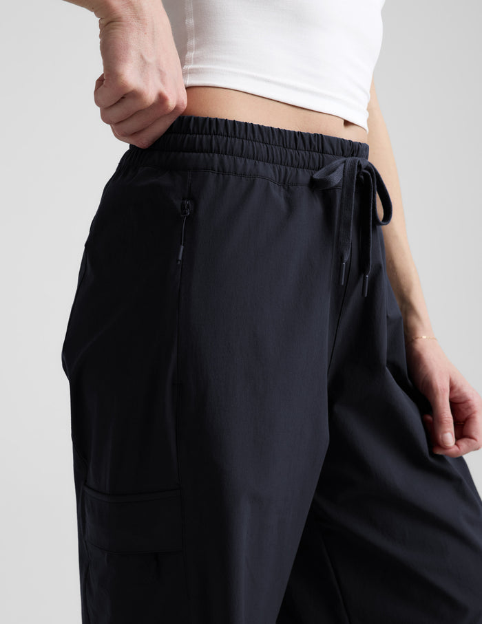 Close-up of Java Peak Pant™ on woman paired with a white crop top, showing the elastic drawstring waist and zipper pocket.