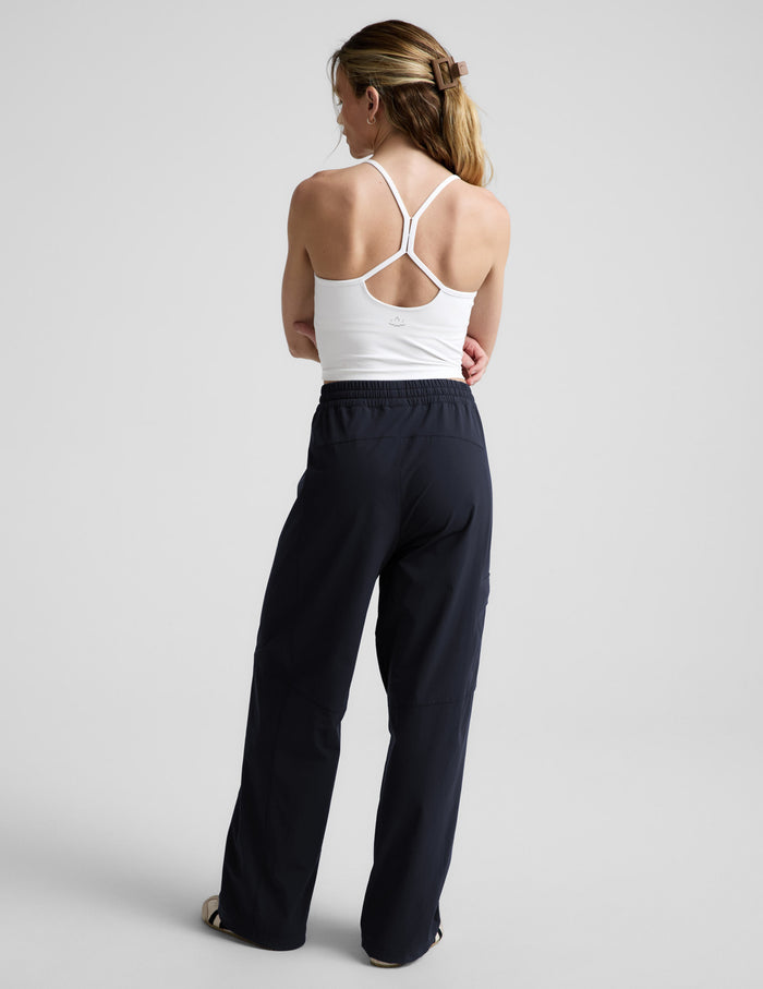 Woman wearing Java Peak Pant from the rear view, paired with a white tank top and featuring an elastic waistband.