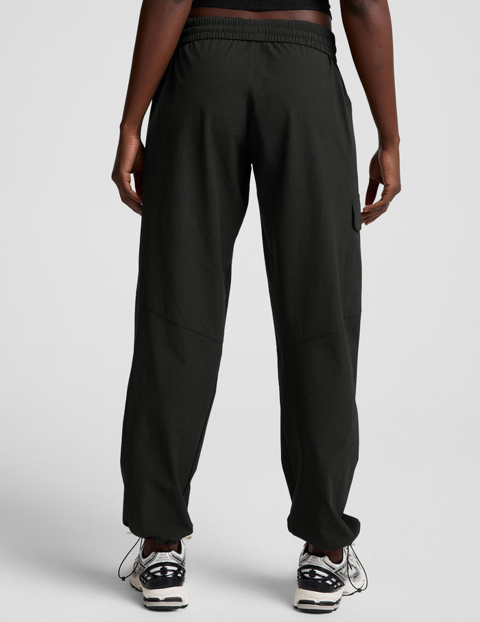 Rear view of woman wearing Java Peak Pant with an elastic waistband, paired with white and black sneakers.