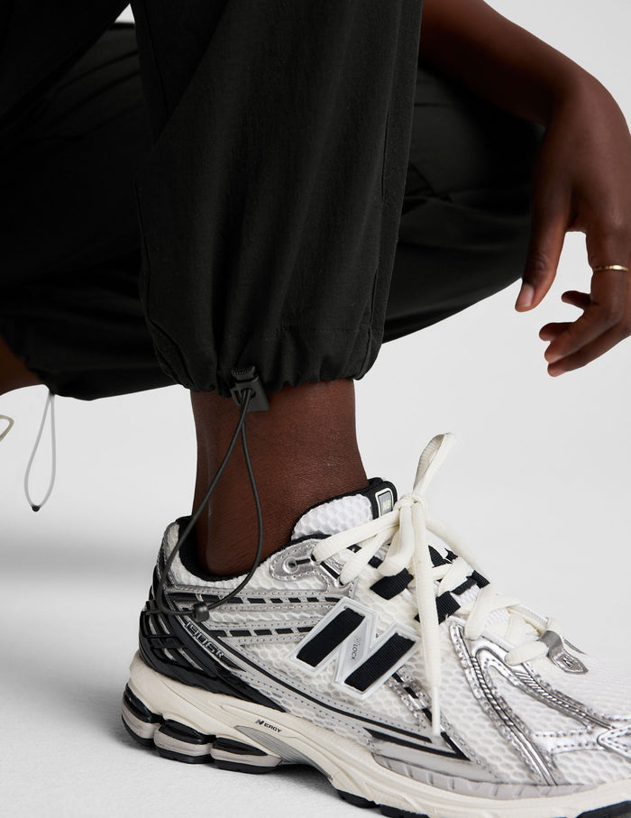 Woman wearing the Java Peak Pant™ paired with white sneakers, featuring a close-up of the adjustable bungee hem.