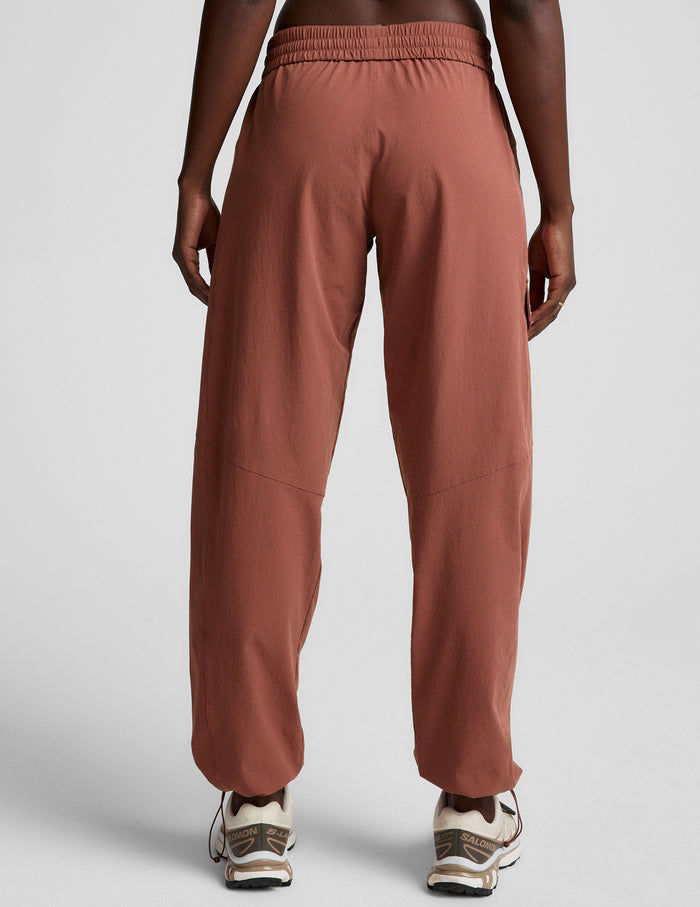 Rear view of woman wearing Brown Peak Pant featuring an elastic waistband, paired with tan sneakers.