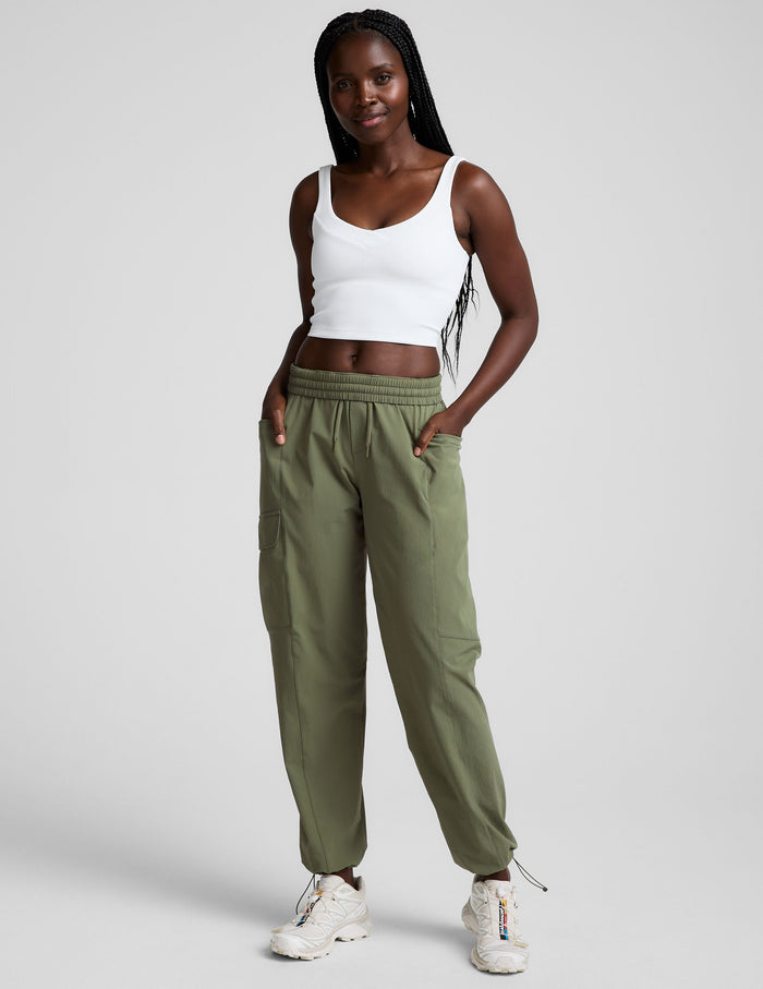 Olive Peak Pant cargo joggers with an elastic waistband and bungee hems on a model wearing a white crop top.