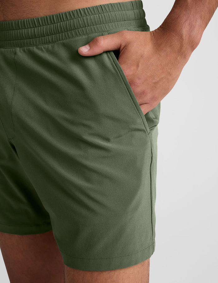 Close-up of olive Pivotal 2.0 Men's Lined Short 7" featuring a hand in the side pocket and gathered elastic waistband.