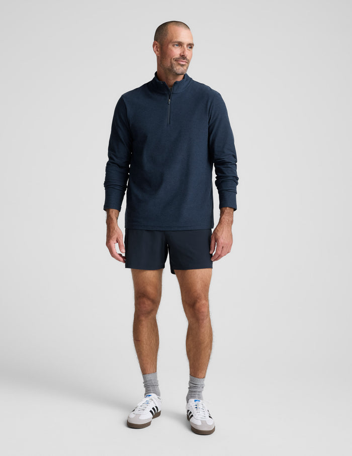 Man wearing a navy long-sleeve shirt and shorts on a white background.