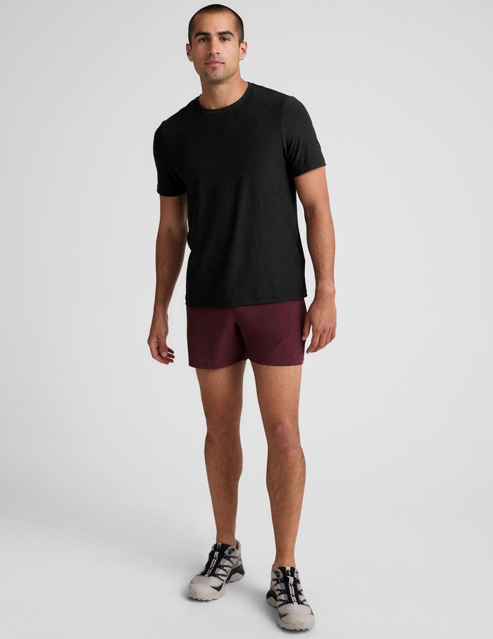 Front view of a man wearing maroon Pivotal 2.0 Men's Short 5" with a black tee, showing the relaxed mid-thigh athletic fit.