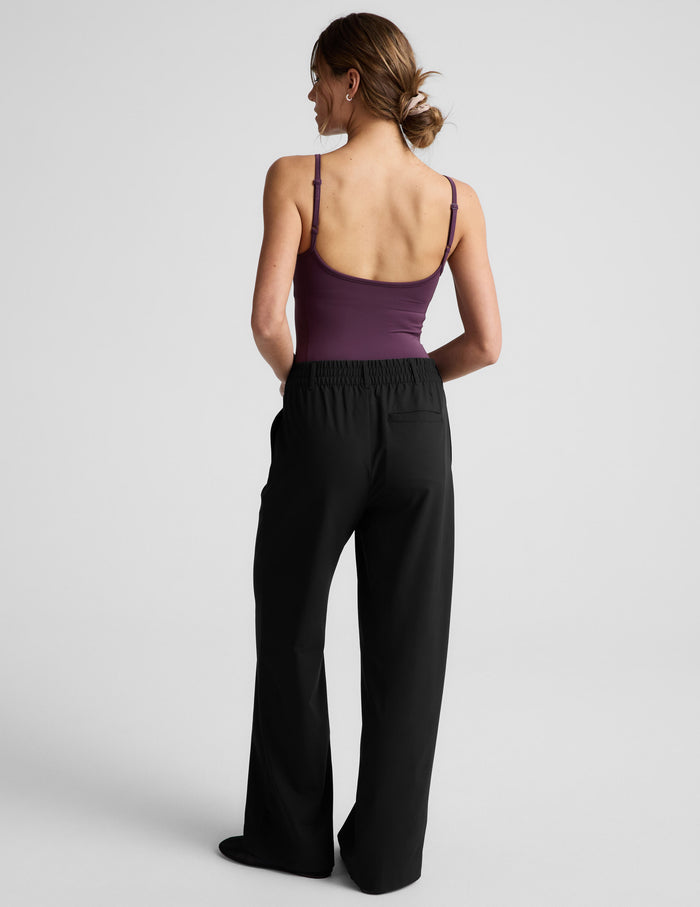Woman wearing a purple bodysuit and black pants against a plain background.