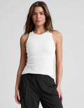 Woman wearing a white high neck ribbed tank top and black pants.