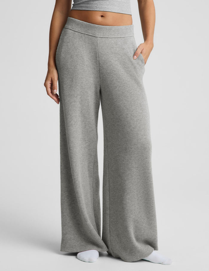 A person wearing heather gray wide-leg sweatpants with a matching cropped top, shown from the waist down against a light gray studio background.