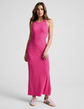 Woman wearing a ribbed pink high-neck maxi dress against a plain background.