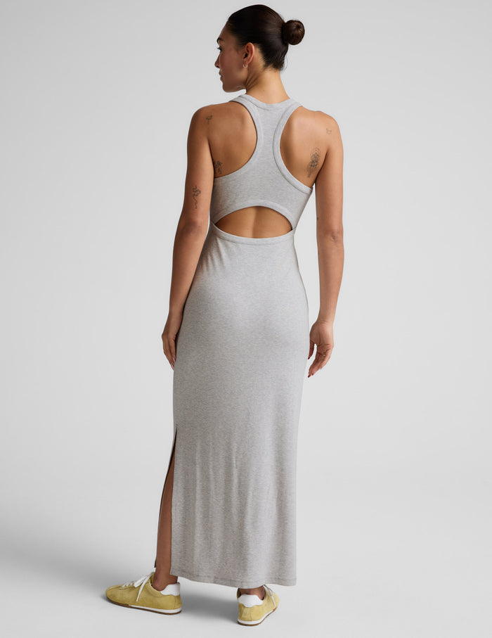 Woman wearing a gray high neck ribbed maxi dress against a plain background.