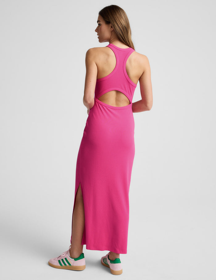 Woman wearing a ribbed pink high-neck maxi dress against a plain background.