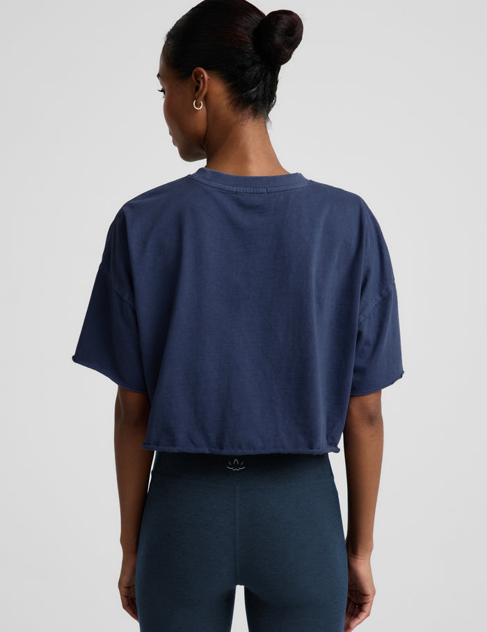 Woman wearing a navy blue cropped t-shirt and navy biker shorts against a plain background.