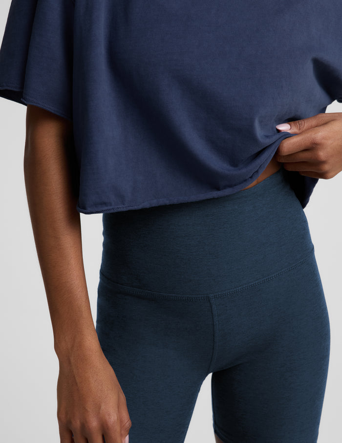 Woman wearing a navy blue cropped t-shirt and navy biker shorts against a plain background.