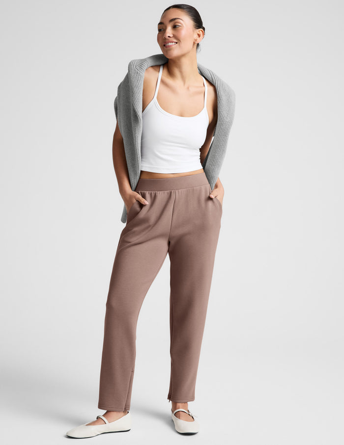 Smiling woman in brown SoftSpring Tapered Pant featuring a mid-rise elastic waist and tapered ankle-length fit.