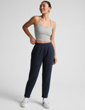 Navy SoftSpring Tapered Pant on a smiling model. Features mid-rise elastic waistband and ankle-length tapered fit.