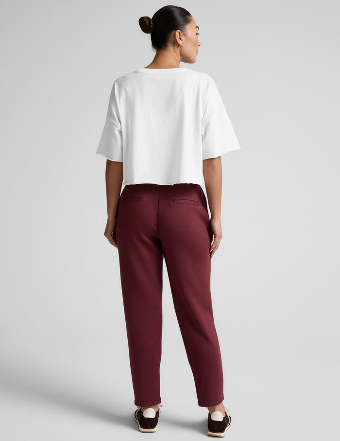 Back view of maroon SoftSpring Tapered Pant on a model, featuring welt pockets and a tailored, ankle-length tapered fit.