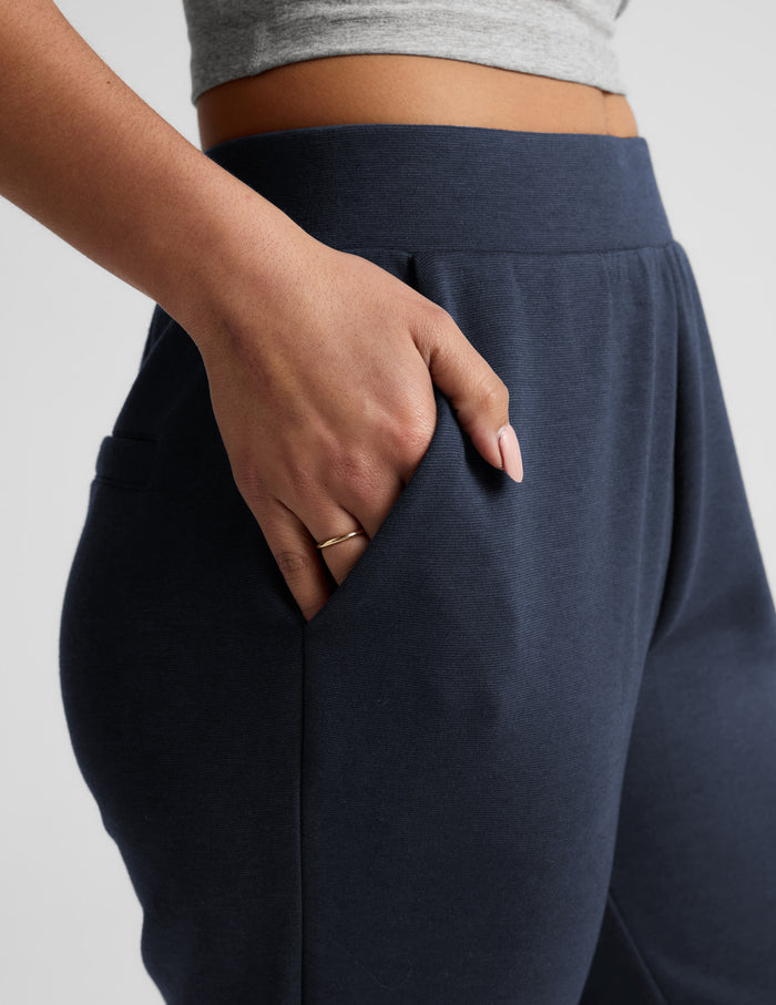 Navy SoftSpring Tapered Pant featuring a mid-rise elastic waistband and a hand resting in the side welt pocket.