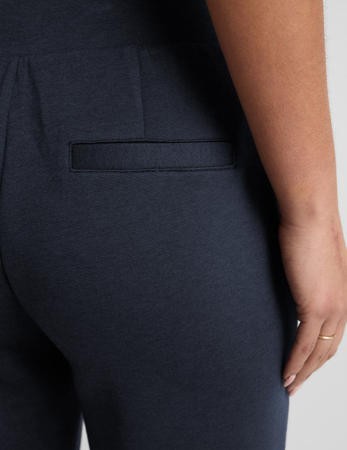 Close-up of the navy SoftSpring Tapered Pant showing a rear welt pocket and dense, textured fabric.