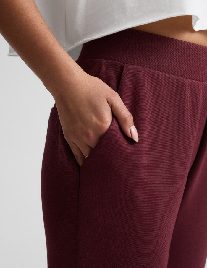 Close-up of the maroon SoftSpring Tapered Pant featuring a hand in the side pocket and comfortable elastic waistband.