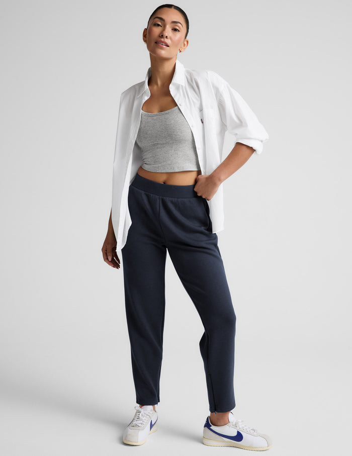 Model stands in navy SoftSpring Tapered Pant, a mid-rise ankle-length tailored sweatpant with an elastic waistband.