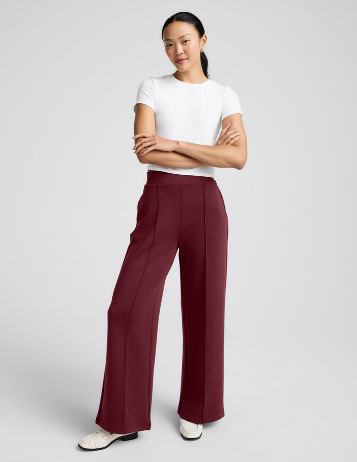 A woman wearing maroon SoftSpring Wide Leg Pant 29" with pintuck seams, a wide leg fit, and a mid-rise elastic waistband.