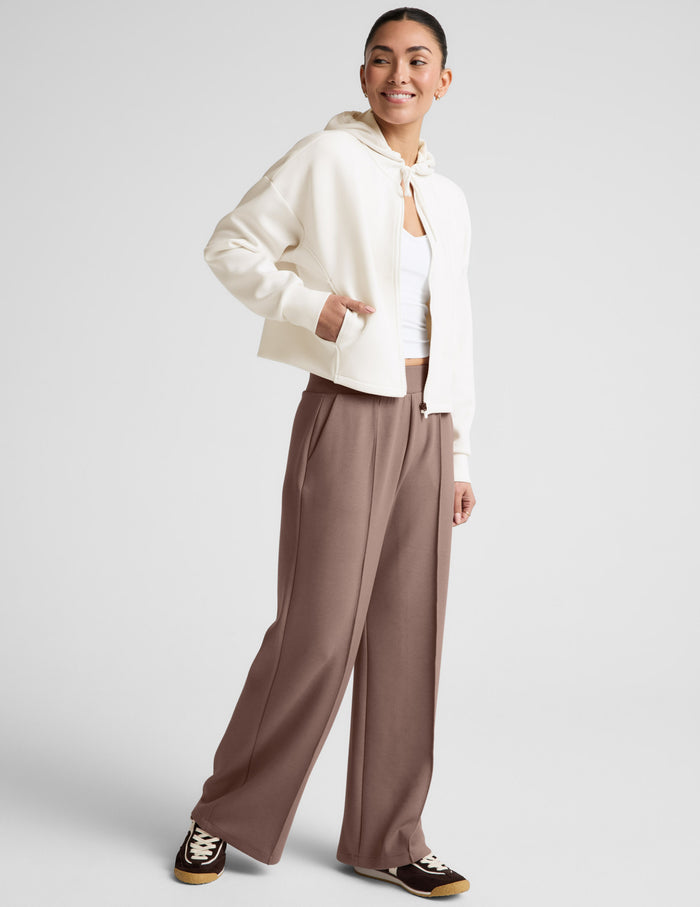 Smiling woman wears SoftSpring Wide Leg Pant in beige featuring front pintucks, wide legs, and mid-rise elastic waistband.