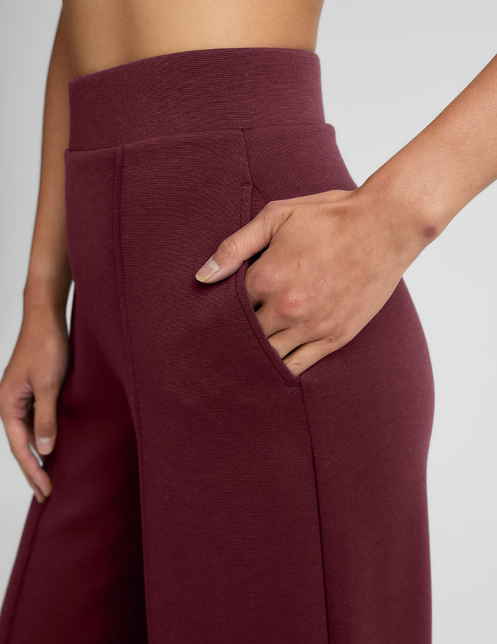 Close-up of maroon SoftSpring Wide Leg Pant showing the elastic waistband, slant pocket, and front pintuck seam.