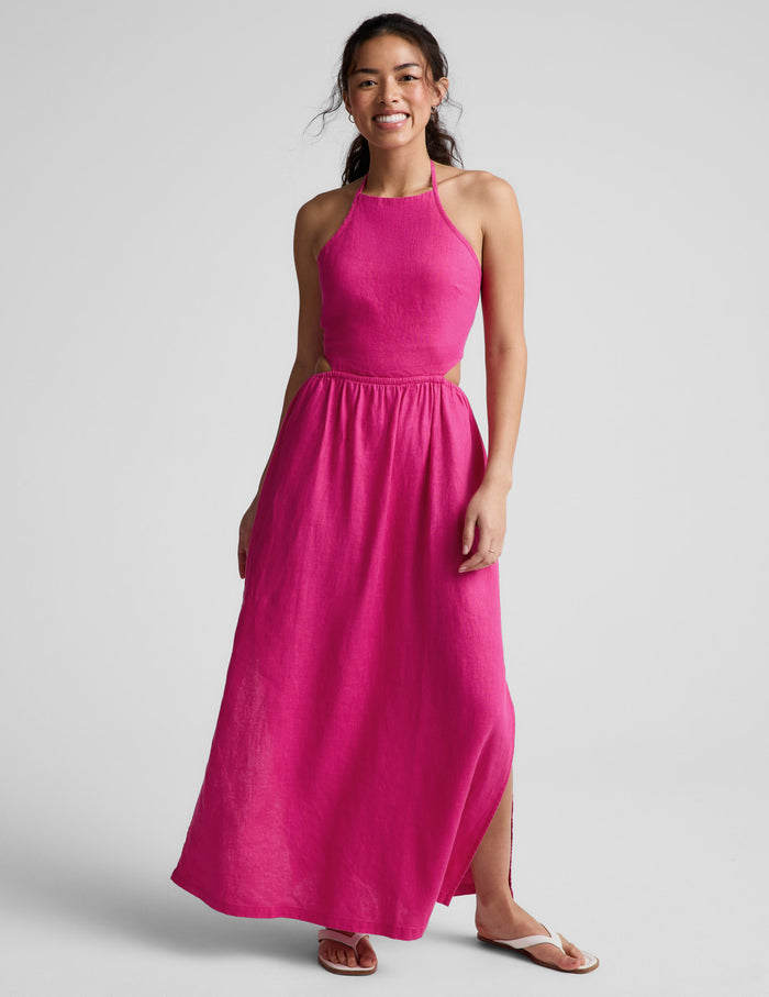 Woman wearing a pink halter neck midi dress on a plain background.