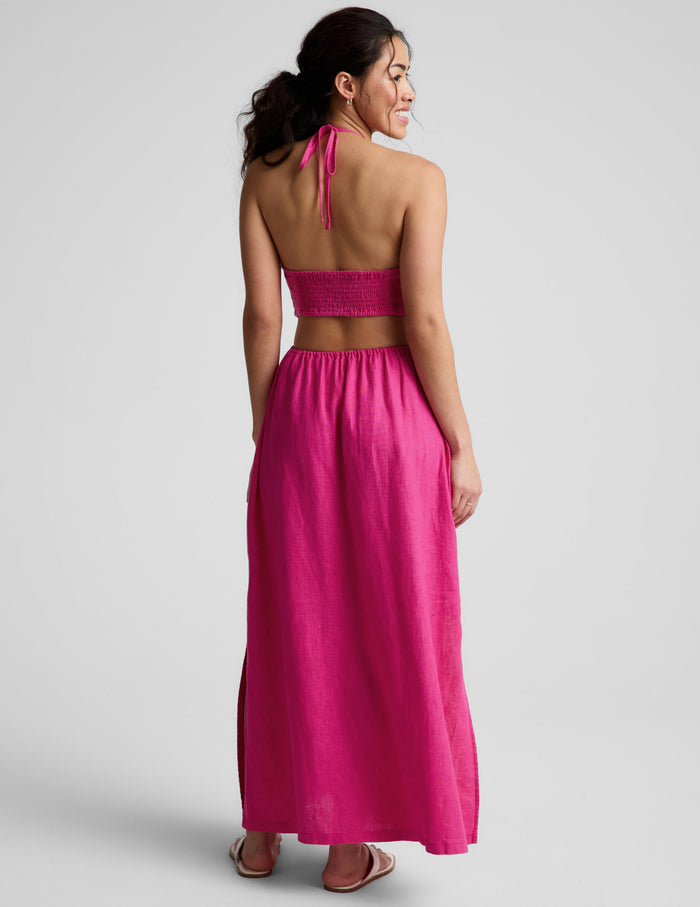 Woman wearing a pink halter neck midi dress on a plain background.