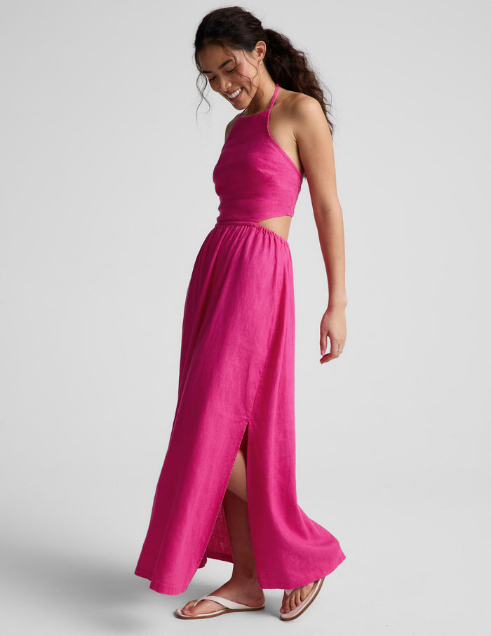 Woman wearing a pink halter neck midi dress on a plain background.