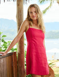 Woman in a red dress standing outdoors with scenic background.