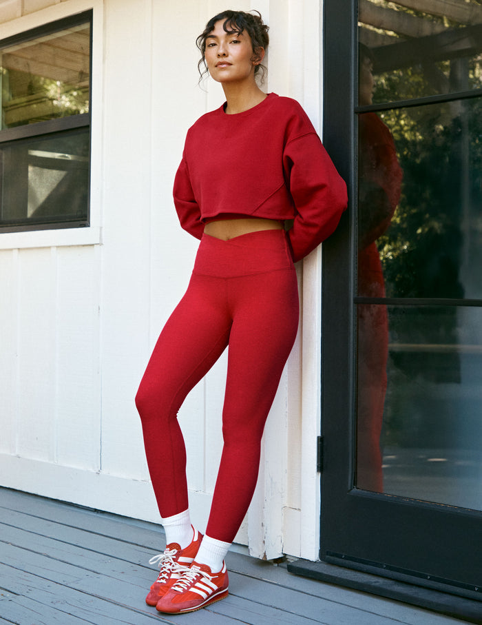 woman wearing a red cropped fleece sweatshirt and red high-waisted midi length leggings with an overlapping waistband.