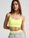 Woman wearing a lime sports bra and gray sweatpants against a plain background.