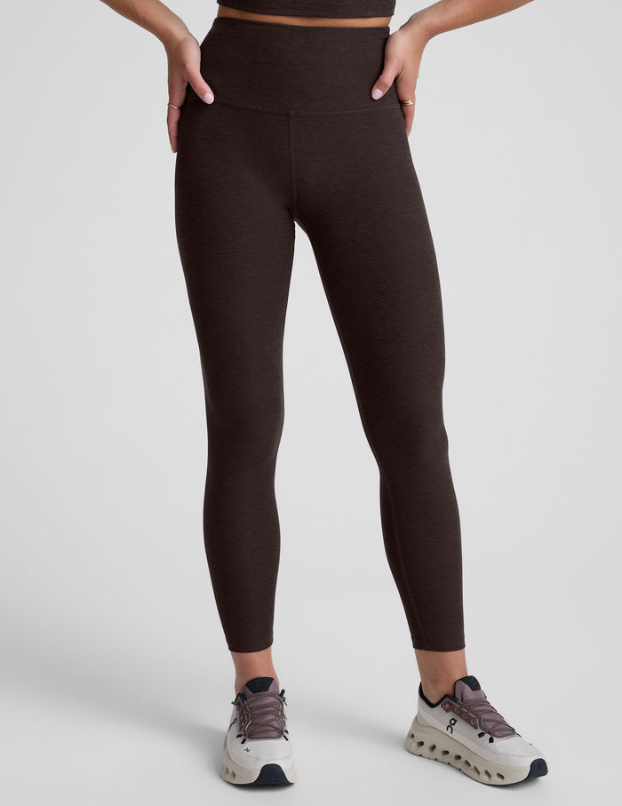 person wearing brown high-waisted midi leggings on a plain background.