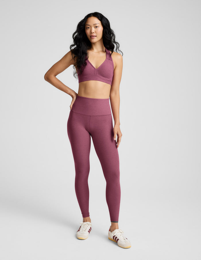 Woman wearing a matching purple sports bra and leggings set on a white background.