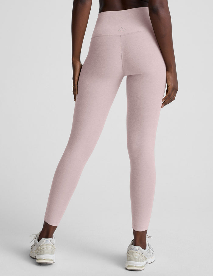 Person wearing light pink leggings on a plain background