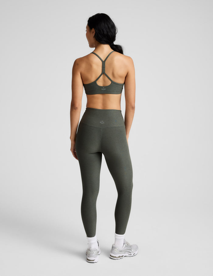 Woman wearing a green sports bra and leggings set on a white background.
