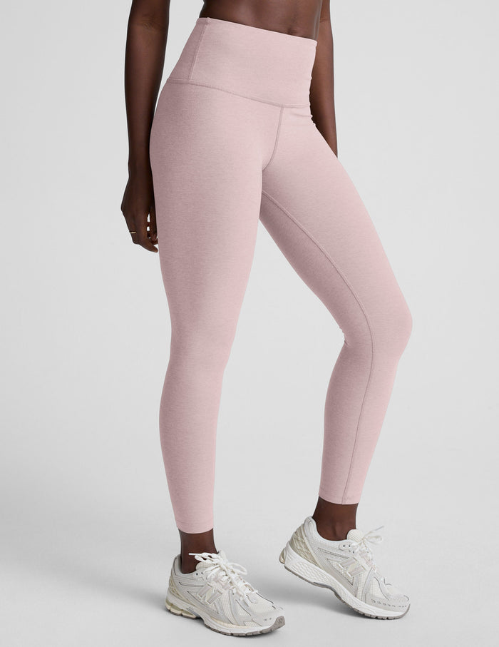 Person wearing pink leggings and white sneakers on a light gray background
