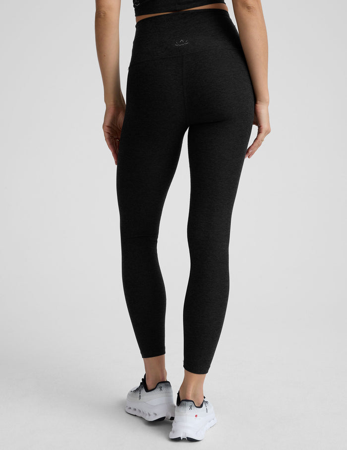 model wearing black high-waisted midi leggings on a white background.