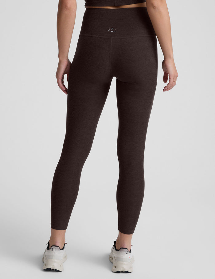 person wearing brown high-waisted midi leggings on a plain background.