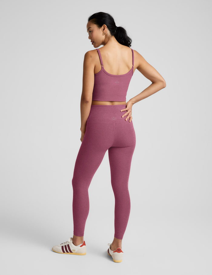 Woman wearing a purple athletic outfit on a light gray background.