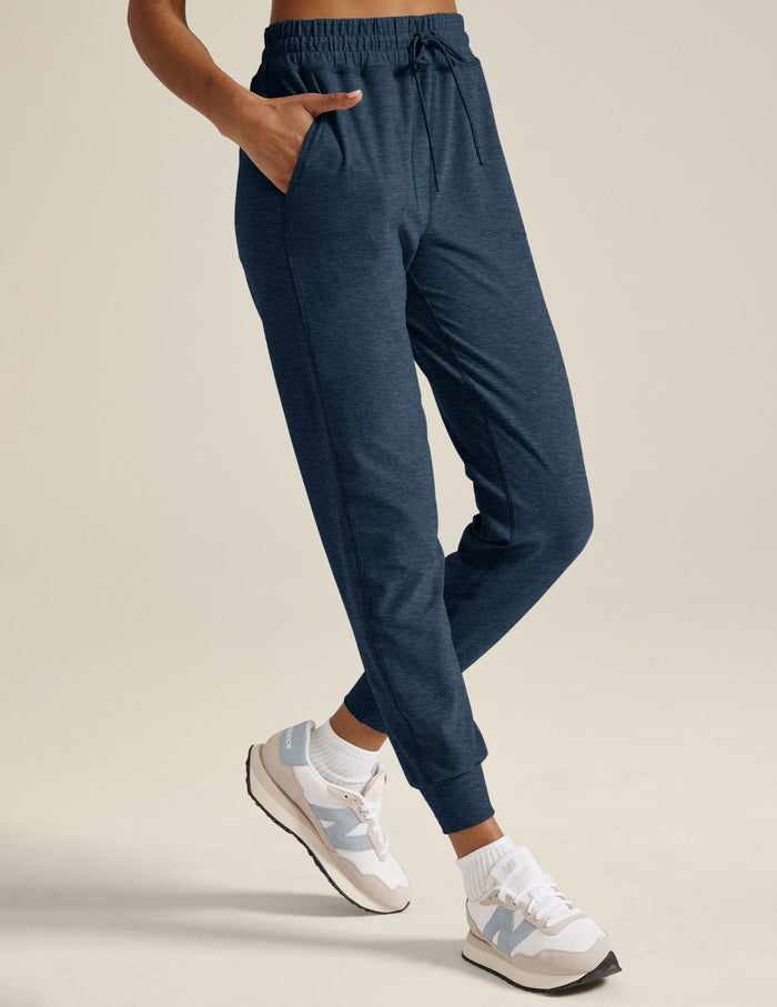 A woman wears the Spacedye Commuter Midi Jogger in Nocturnal Navy, featuring a slim fit, drawstring waist, and side pockets.